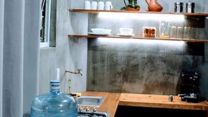 A compact kitchen with a large water dispenser, a sink, and shelves with kitchenware. - Quiet stay near Zócalo · Wi-Fi · Terrace · Walkable · For 2 guest (Oaxaca de Juárez)