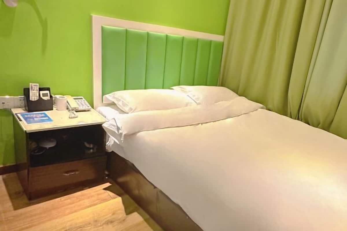 Habitación de hotel con cama, mesita de noche, teléfono y una pequeña mesa con una revista.