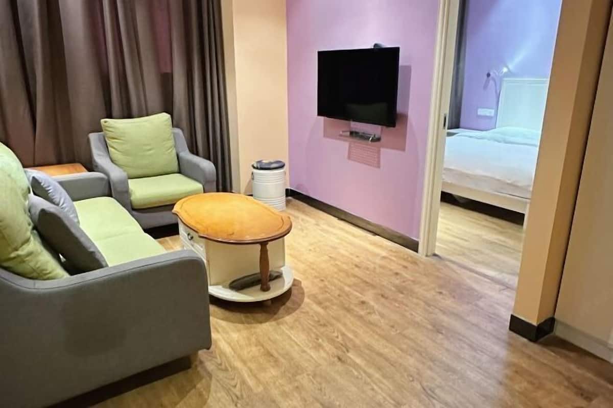 Una habitación de hotel con un sofá, una pequeña mesa redonda, un televisor y una cama.