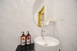 A bathroom with a white sink, a mirror, and two bottles of shampoo. - Aierma Fashion Hotel (Zhengzhou Zhongyuan Wanda City Center Hospital Subway Station) (Zhengzhou)