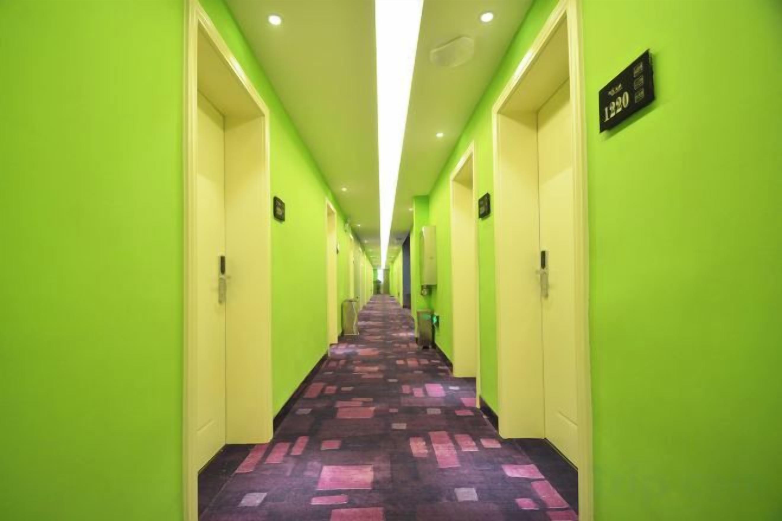 A hotel corridor with a check-in counter, doors, and a carpeted floor.