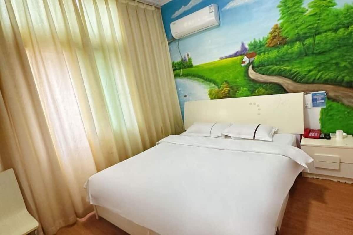 Una habitación de hotel con una cama, una mesita de noche, una lámpara, un cuadro de un paisaje y una ventana con cortinas.