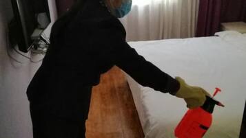 A person cleaning a bed with a spray bottle.