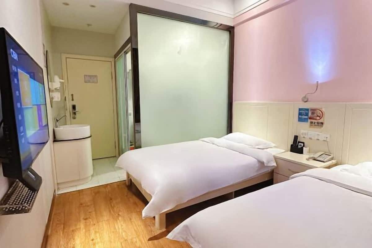Habitación de hotel con dos camas, un escritorio, un teléfono, una computadora portátil y un televisor.