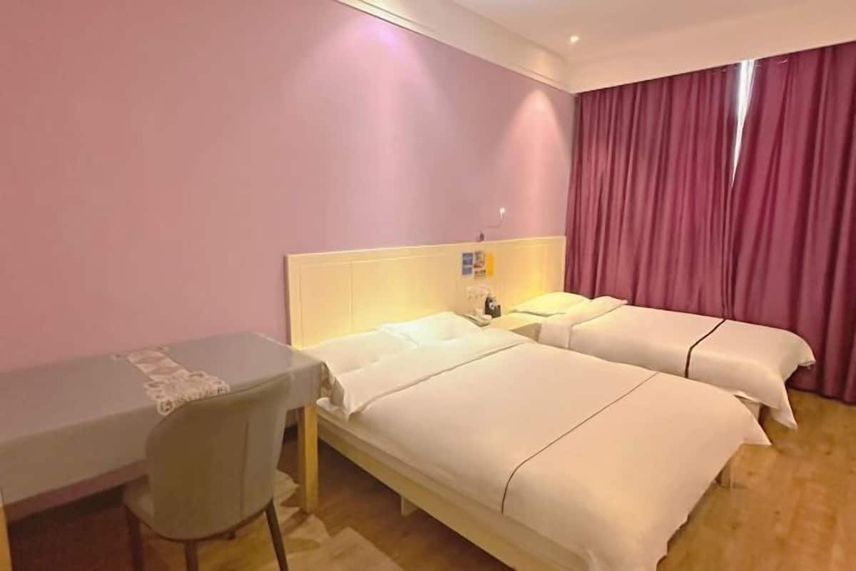 Una habitación de hotel con dos camas, un escritorio y una silla.