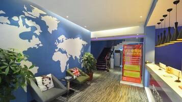 A lobby with a world map on the wall, a reception desk, and a staircase.
