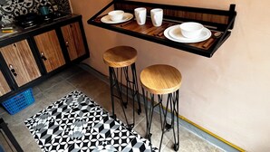 A compact kitchen with a small dining area, including a wooden table with stools, a tray with cups and plates, and a patterned floor. - Quiet stay near Zócalo · Wi-Fi · Terrace · Walkable · For 2 guest (Oaxaca de Juárez)