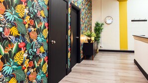 A hallway with a vibrant mural, a clock, and a yellow accent wall.