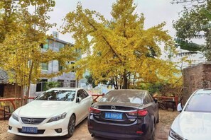 A parking area with two cars parked under trees. - Wang Xing Hotel (Nanxiong)