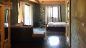 A room with a bed, a sofa, a fan, and a window with curtains.