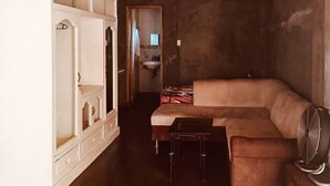 A room with a sofa, a small table, a cabinet, and a mirror.