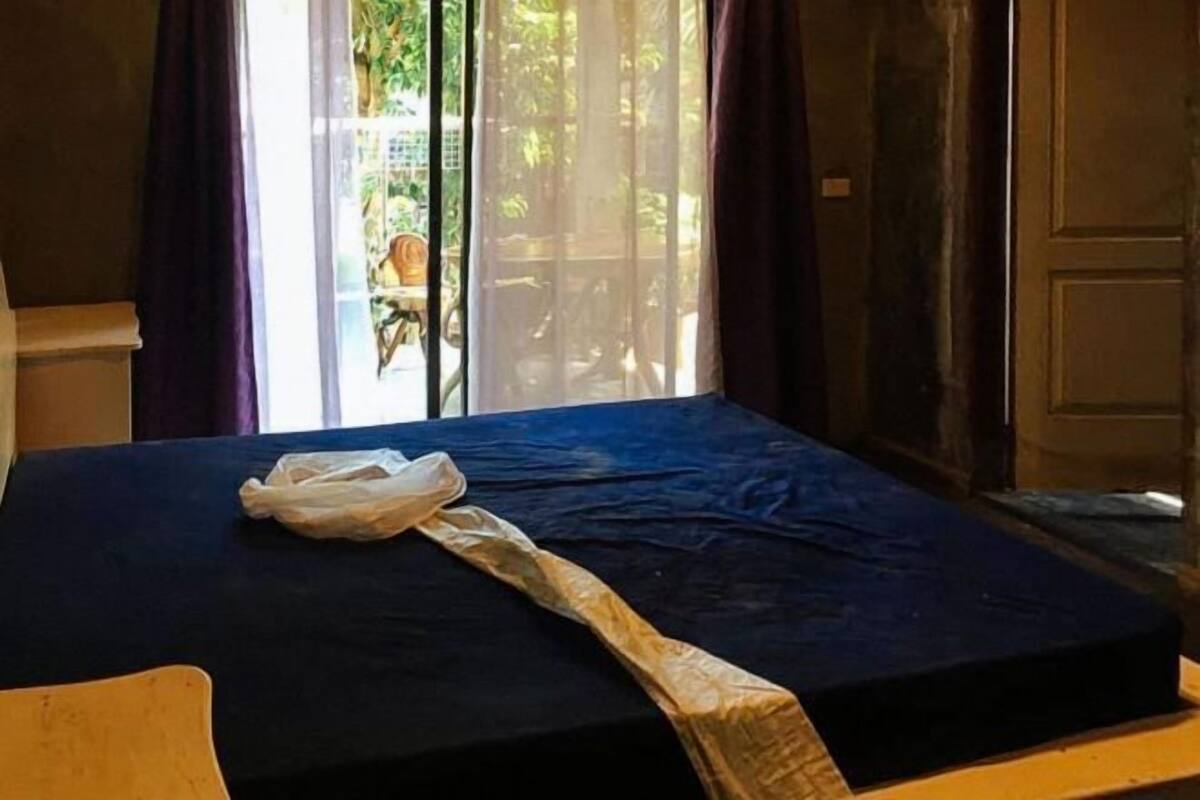 A room with a bed, a chair, and a window with curtains.