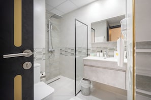 A modern bathroom with a glass-enclosed shower, a toilet, and a sink with a mirror above it.