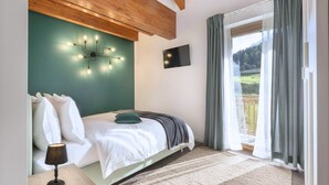 A bedroom with a bed, a wall-mounted TV, a window with curtains, and a view of a landscape. - Sesto Senso - Three Bedroom Apartment, Sleeps 8 (Ponte di legno)