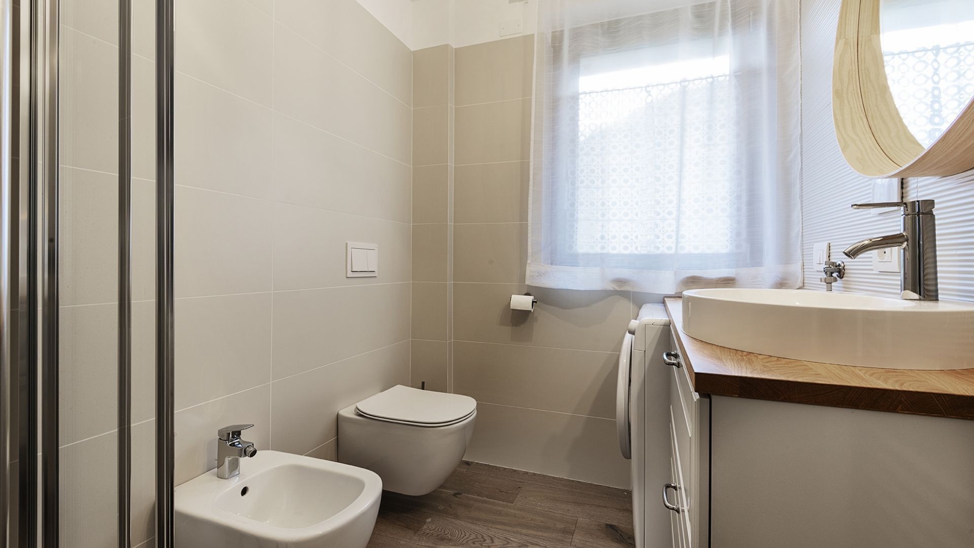 A bathroom with a bidet, toilet, sink, and mirror.