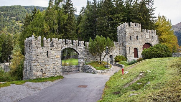 A stone castle with a gate, surrounded by trees and a grassy hill. - Sesto Senso - Three Bedroom Apartment, Sleeps 8 (Ponte di legno)