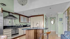 Una cocina moderna con una isla central, electrodomésticos de acero inoxidable y un taburete de bar.