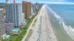 A beachfront hotel with multiple high-rise buildings, a long sandy beach, and a clear view of the ocean. - Carolinian 1732-Oceanfront 2BR/2BA-Pool (Myrtle Beach)