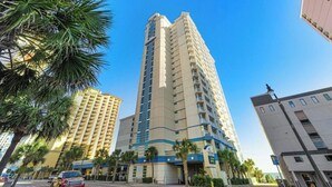 A high-rise hotel with multiple floors, a prominent entrance, and a view of the ocean. - Carolinian 1732-Oceanfront 2BR/2BA-Pool (Myrtle Beach)