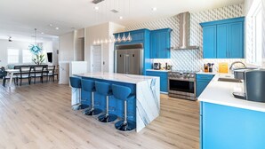 A modern kitchen with blue cabinets, a marble island, and stainless steel appliances. - Spacious new build 6-bedroom 6.5 bath house in gorgeous Navarre Beach (Navarre)