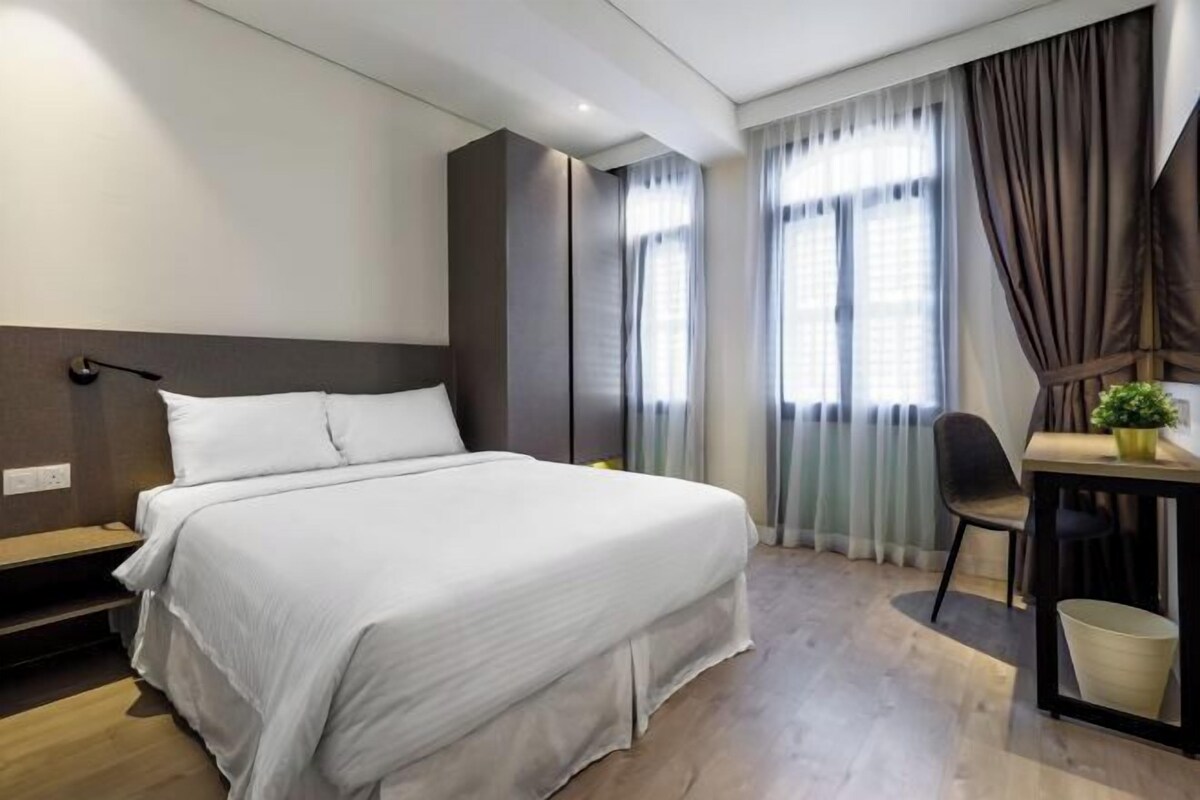 Ein modernes Hotelzimmer mit einem Bett, einem Schreibtisch und einem Stuhl.
