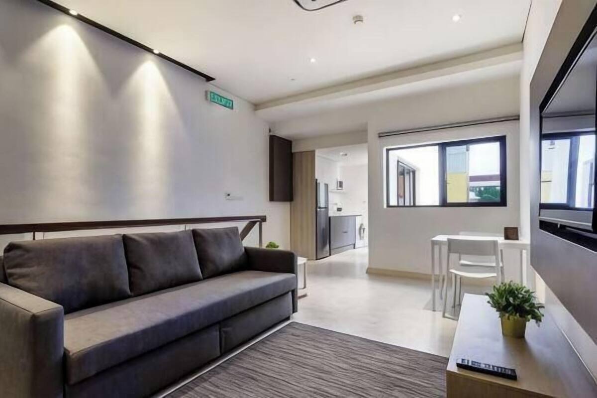 A modern living room with a sofa, a small table, and a TV.