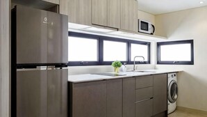 Une cuisine moderne équipée d’un réfrigérateur encastré, d’un four à micro-ondes, d’un évier et d’un lave-linge.