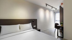 Une chambre d’hôtel moderne, dotée d’un grand lit, d’un bureau et d’une chaise.
