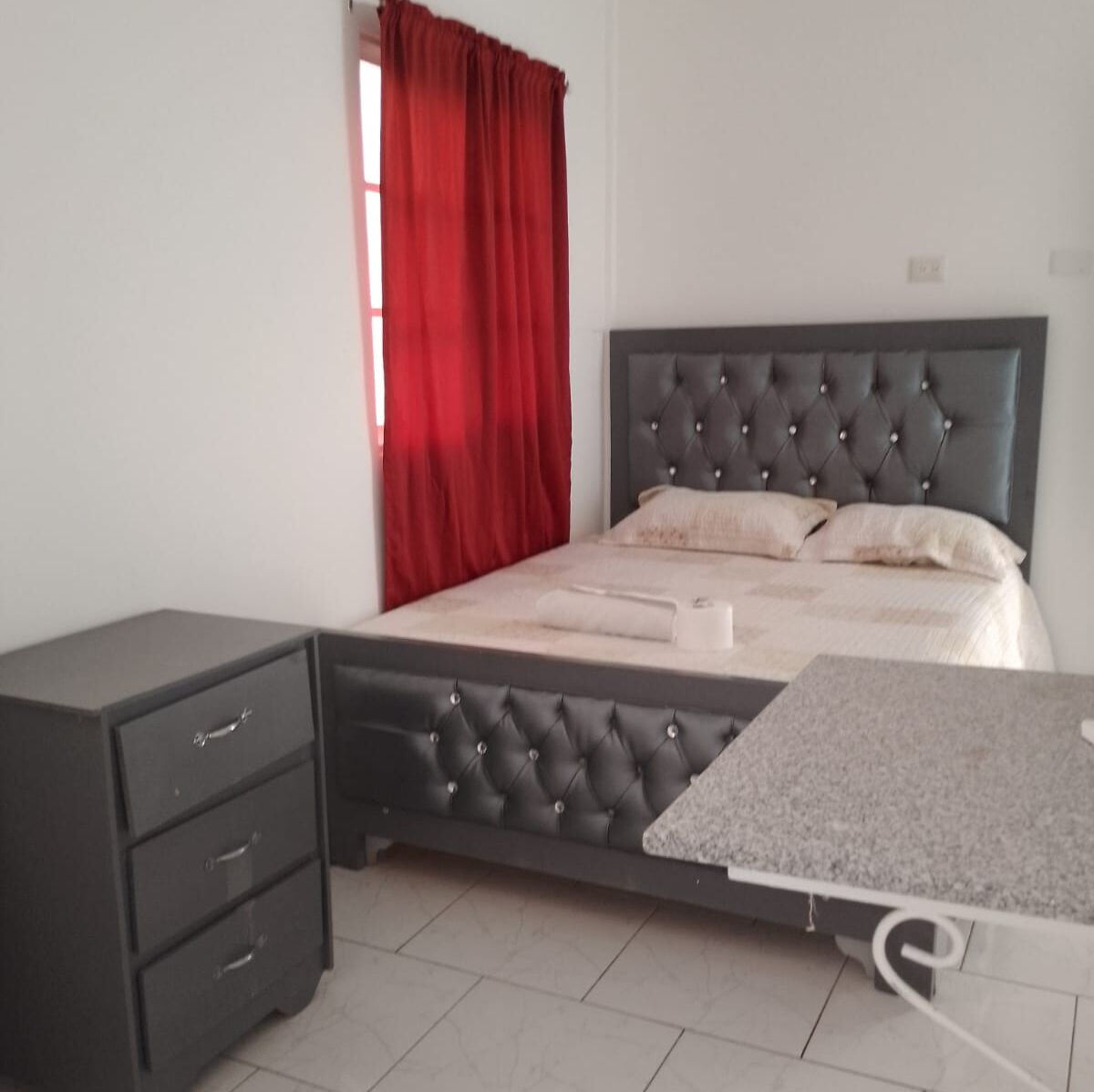 Un dormitorio con una cama, una mesita de noche y un escritorio.