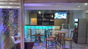Een bar met krukken, een toog en een televisiescherm.