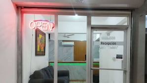 Een hotel receptie met een glazen deur, een neonbord dat 'OPEN' aangeeft en een receptiebalie.