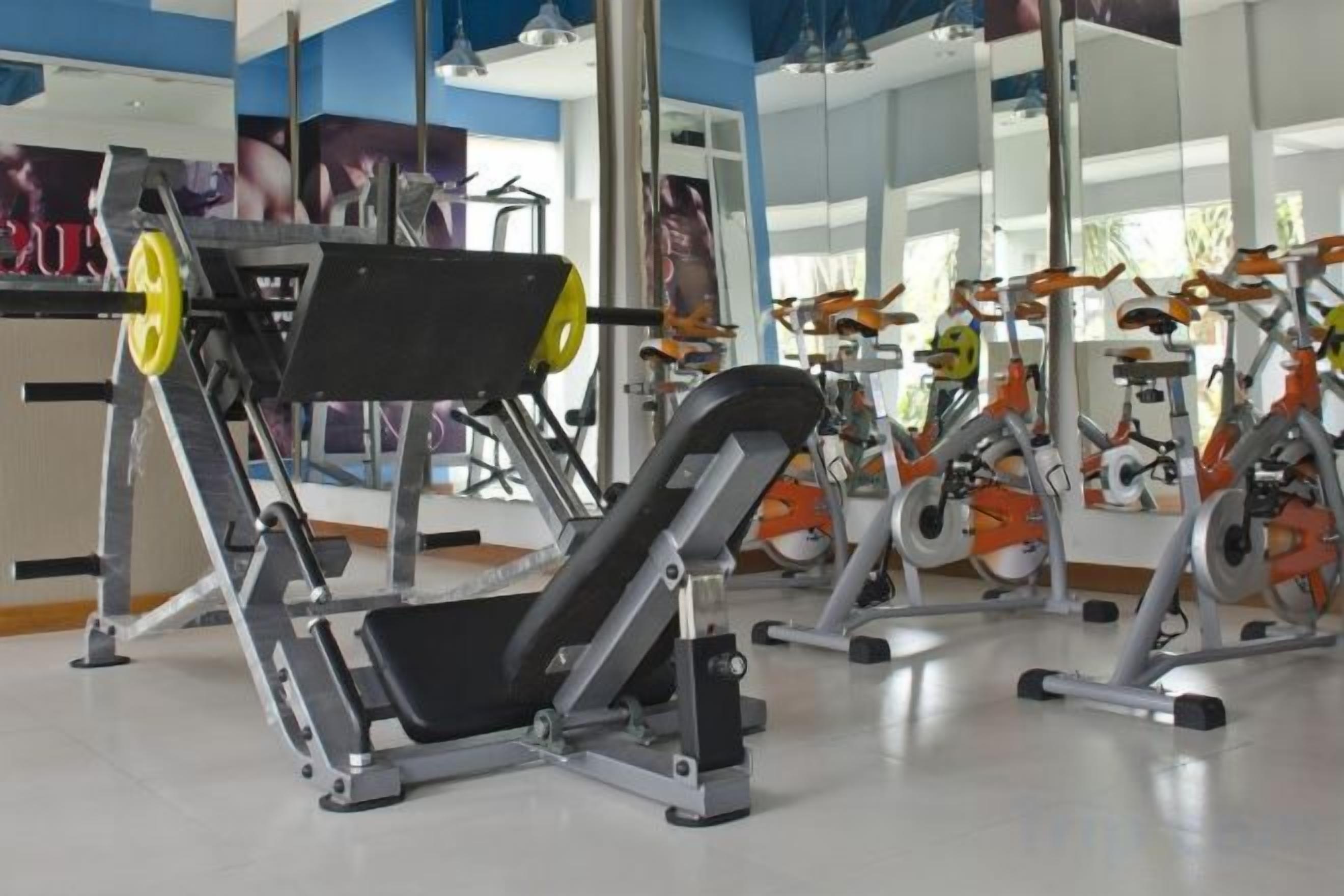 A gym with exercise equipment, mirrors, and a clean floor.