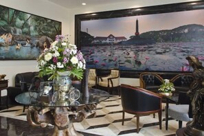 A room with a large painting of a landscape, a table with a vase of flowers, and several chairs. - Ijen Suites Resort & Convention (Klojen)