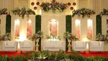 A stage with white chairs, floral arrangements, and vertical light panels.