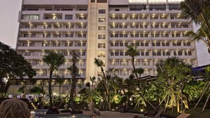 A multi-story hotel with balconies, a pool area with palm trees, and a well-lit facade. - Ijen Suites Resort & Convention (Klojen)