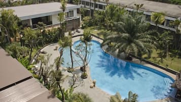 Une piscine entourée de palmiers et un bâtiment doté d’un toit plat.