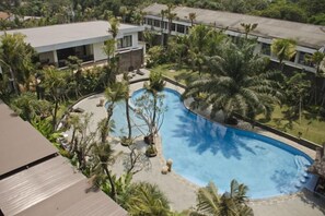A swimming pool surrounded by palm trees and a building with a flat roof. - Ijen Suites Resort & Convention (Klojen)
