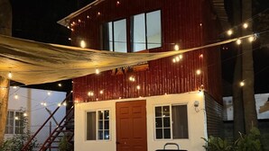 Una casa con fachada roja, una puerta de madera y una parrilla en el patio delantero.