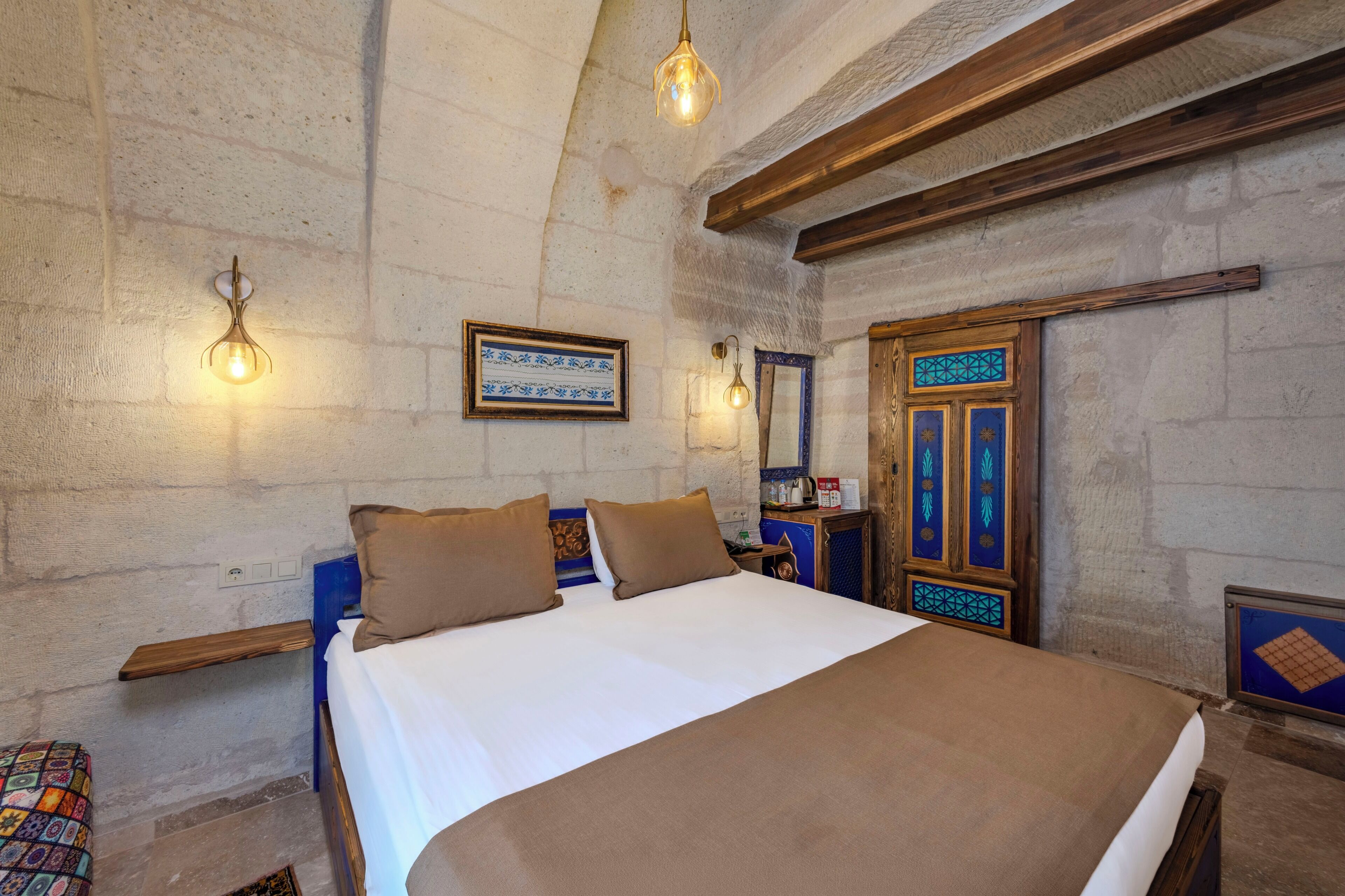 Un dormitorio con cama, dos lámparas de pared, un armario de madera y un espejo decorativo.