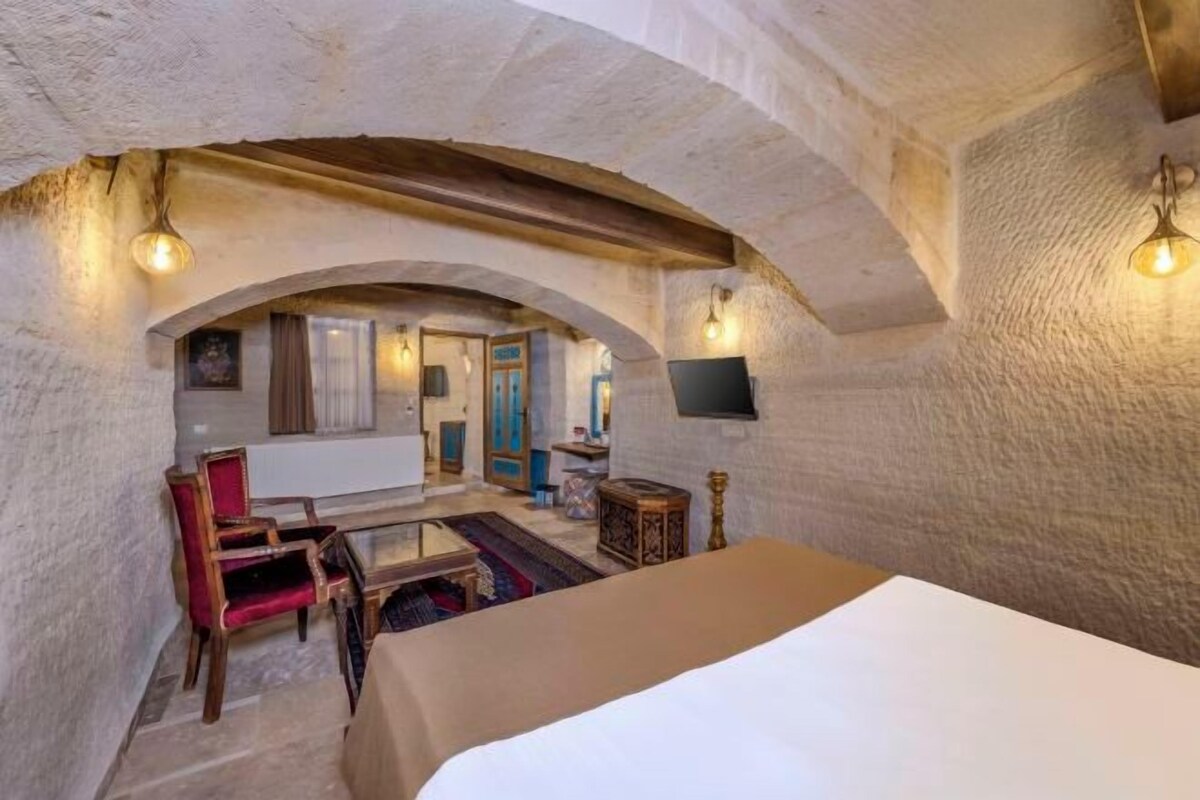 Une pièce comprenant un lit, un bureau et une chaise, avec un téléviseur fixé au mur et une fenêtre.