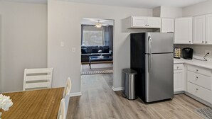 Una cucina compatta con mobili bianchi, un frigorifero in acciaio inossidabile e una macchina per il caffè.