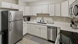 Una cucina moderna con mobili bianchi, elettrodomestici in acciaio inossidabile e un forno a microonde.