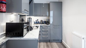 A compact kitchen with grey cabinets, a black microwave, and a coffee maker.