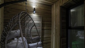 A room with a hanging chair, a window, and wooden paneling.
