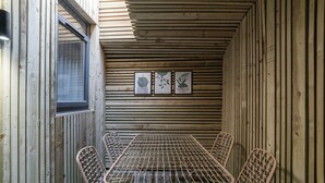 A wooden-paneled room with a table and four wicker chairs.