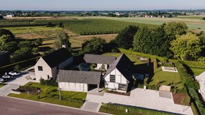 Une maison moderne, dotée d’un toit en pente, entourée d’une pelouse bien entretenue et d’un vignoble.