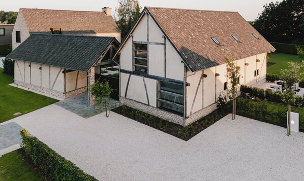 A modern two-story house with a sloped roof, large windows, and a visible staircase leading to the upper floor. - B&B Entre Nous (Herk-de-Stad)