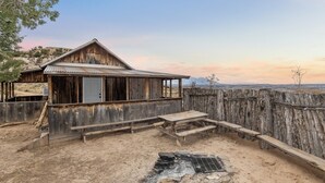 A rustic wooden cabin with a metal roof, a wooden porch, and a stone fire pit. - The Sunset Retreat Cabin (Monticello)