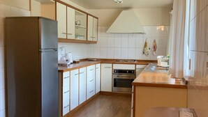 A modern kitchen with a refrigerator, oven, and wooden cabinets. - Colonial House, beautifull spacious garden house  (La Paz)