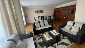 A living room with two sofas, a coffee table, and a dining area with chairs and a table. - Colonial House, beautifull spacious garden house  (La Paz)